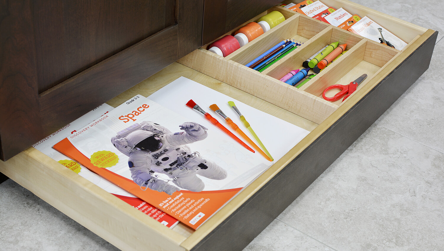 Miscellaneous items can find a home in a Dura Supreme Toe Space Drawer hidden at the foot of your cabinets. Add a Cutlery Divider for the extra organization to create a dedicated place for storing arts, crafts, and homework supplies. Place this solution near the dining room, a kitchen peninsula, or kitchen island where your household often sits to create a workstation that’s easy to access and clean up.