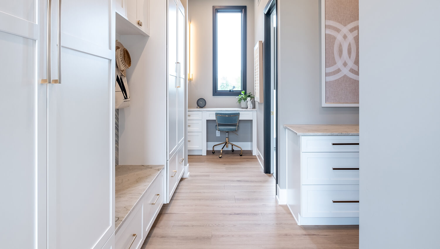 A long hallway with a entryway boot bench and locker system with a small home office desk.