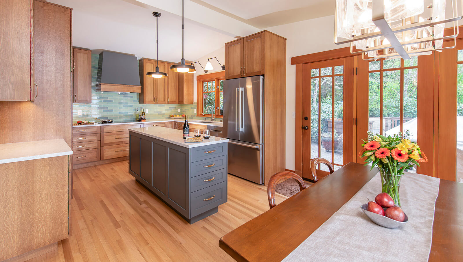 A two-toned Craftsman style kitchen design with a U-Shaped kitchen layout and kitchen island in center with a modern wood hood.