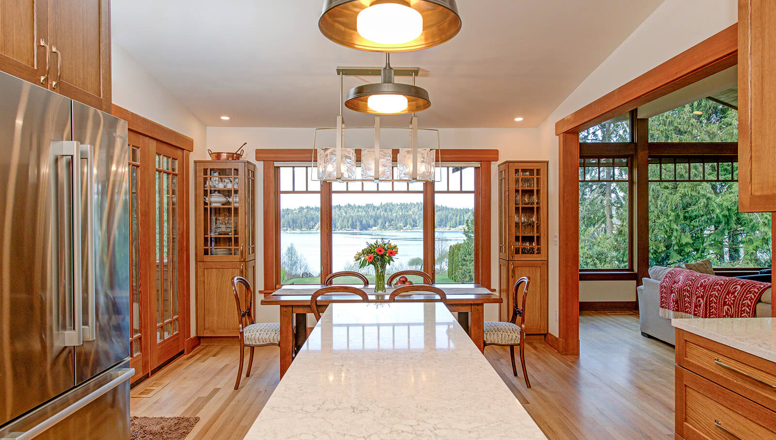 A view from the kitchen into the dining room of a craftsman styled home. The dining room features historic inspired built-in hutches that match the kitchen cabinets.