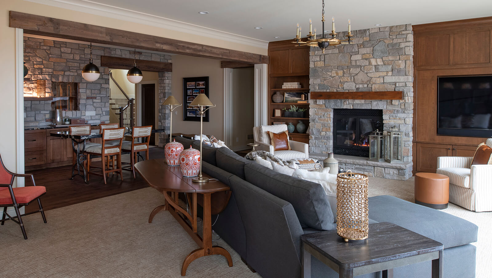 This Craftsman style entertainment room has a large wet bar area and an entertainment center wall with a fireplace.