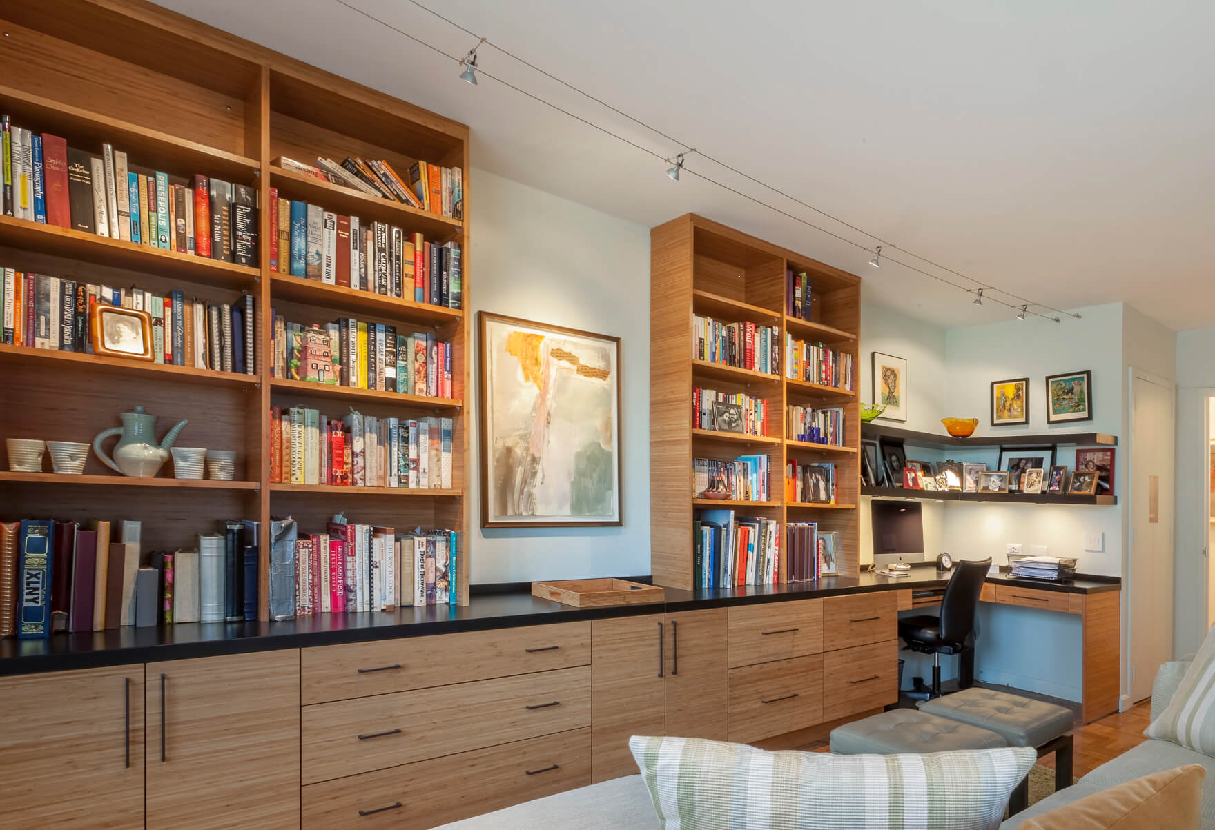 A condo featuring warm yet modern built-in bookcases and a desk area in Dura Supreme's Metro-Horizontal door style in Natural Bamboo Exotic Veneer.