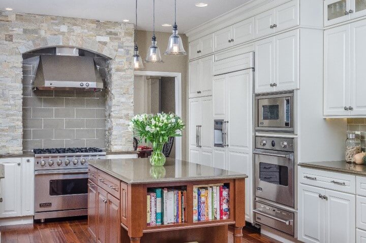 Beautiful Alaska Kitchen design with white painted cabinets and a furniture styled cherry kitchen island with a red stain color.