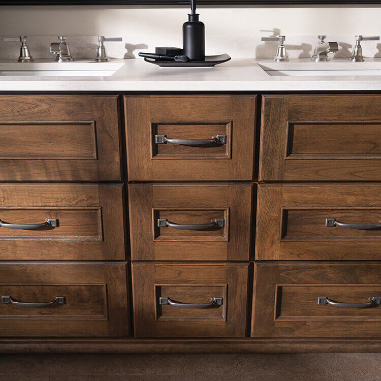 A close up of a furniture style vanity with cherry wood cabinets.
