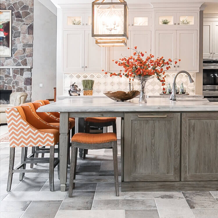 A white painted kitchen with a pretty, rustic kitchen island with light gray weathered wood cabinets from Dura Supreme.