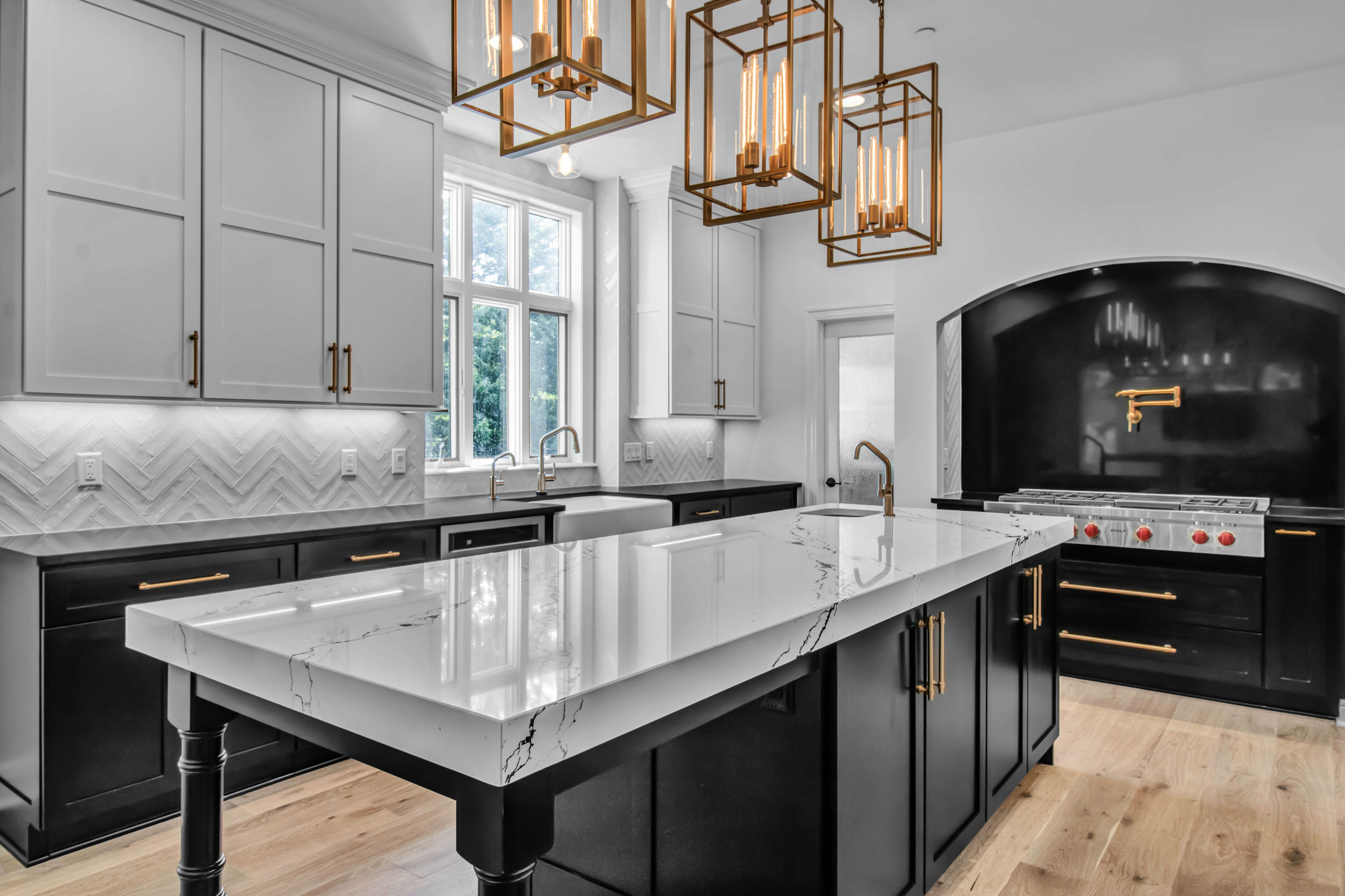 A beautiful black and white kitchen design with an arched frame over the range alcove space and a long, black kitchen island.