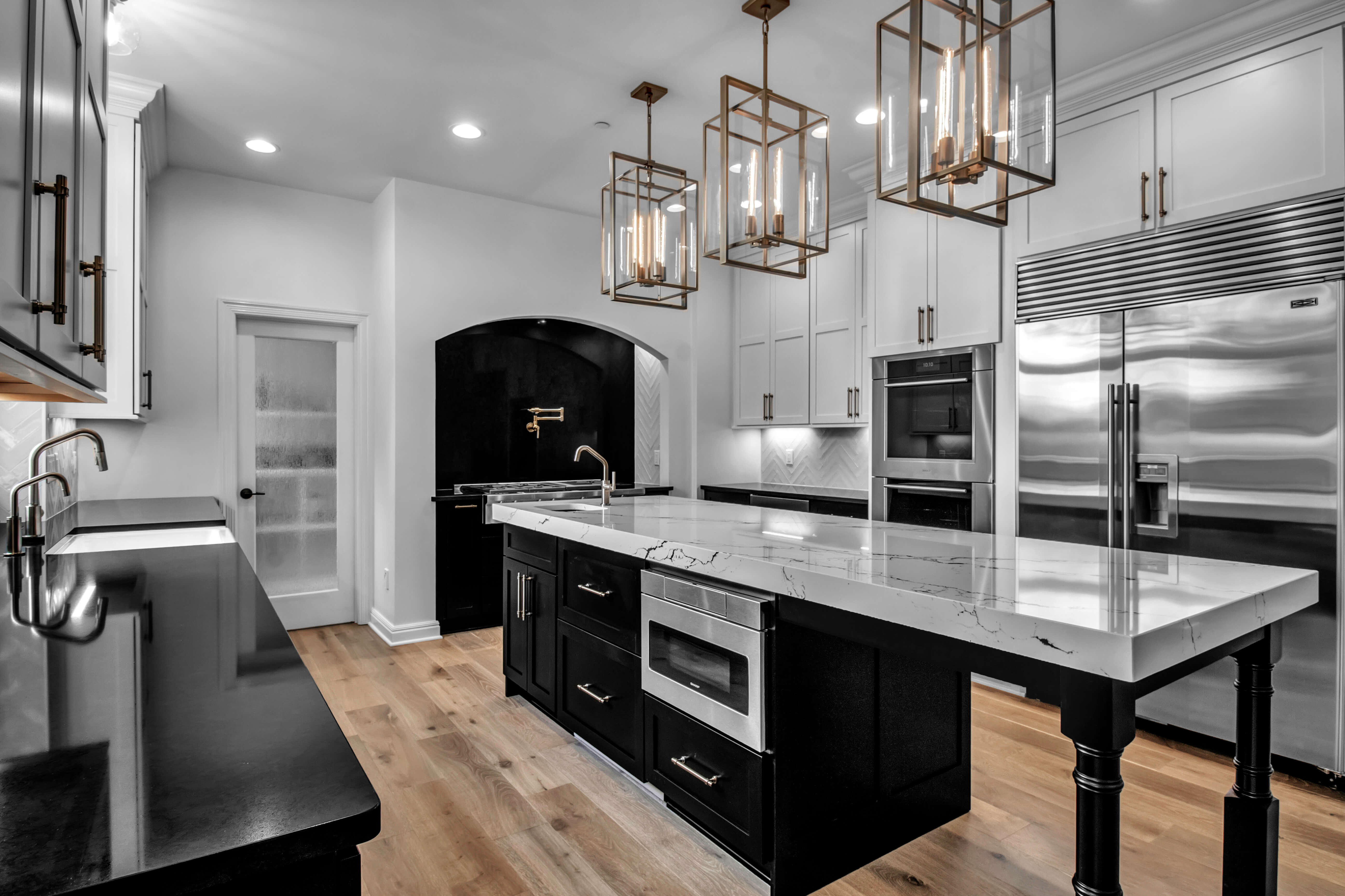 A stunning black and white kitchen with an arched range alcove space and a long table styled kitchen island.