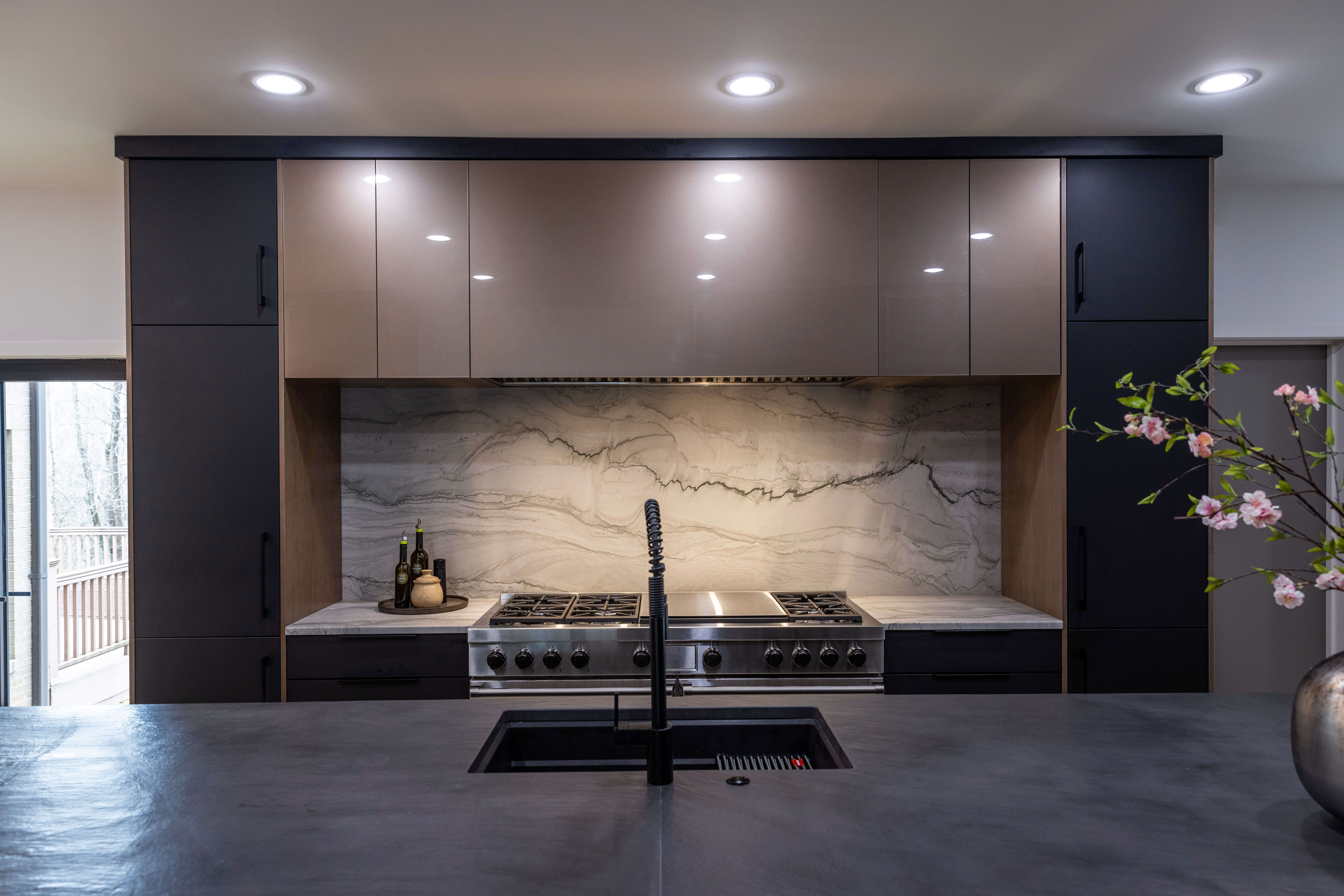 A modern two-toned kitchen design with a large range alcove space that creates a dedicated work zone for cooking.