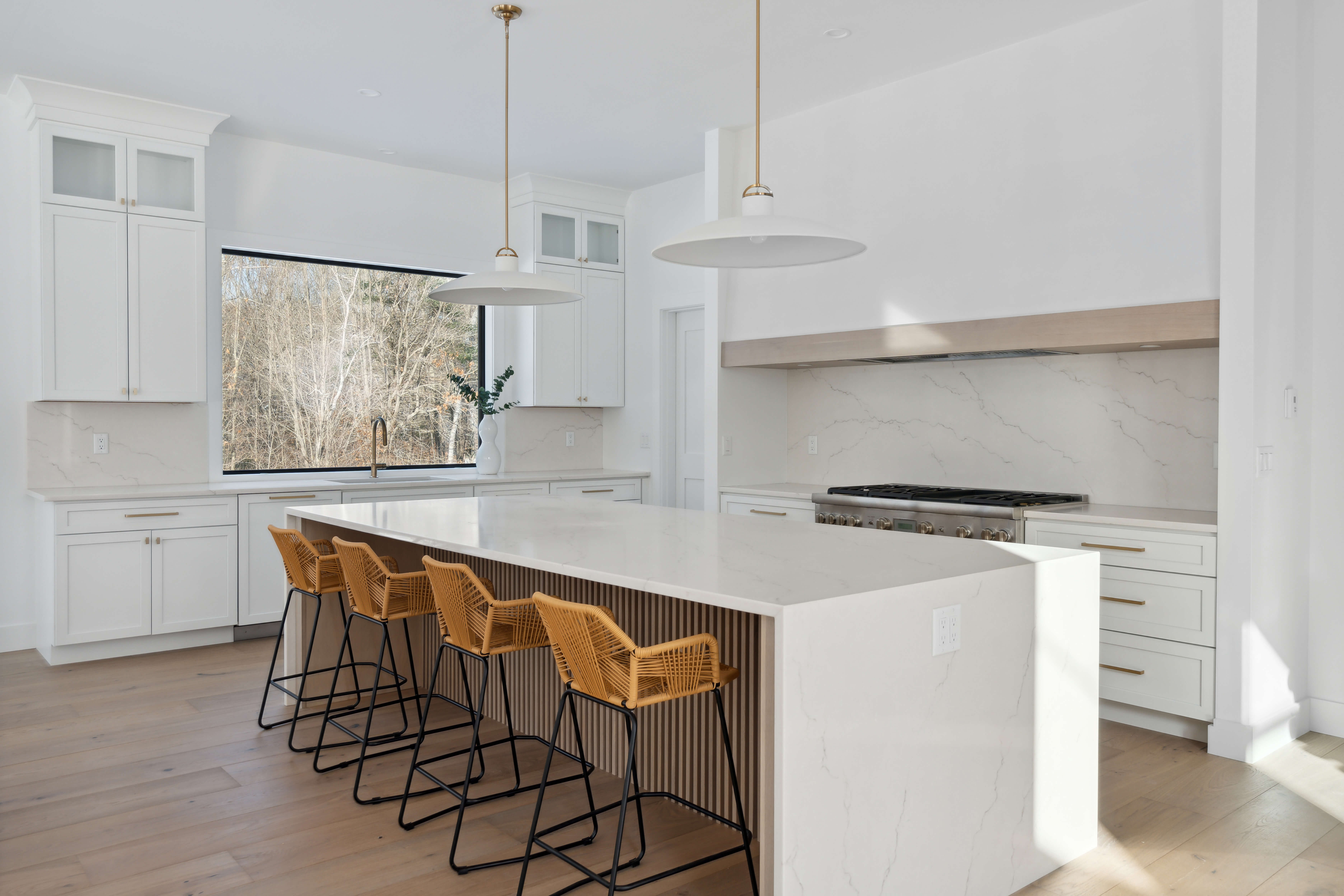 A soft, white and light wood kitchen design with a large range alcove space accented by a wood panel, lintel.