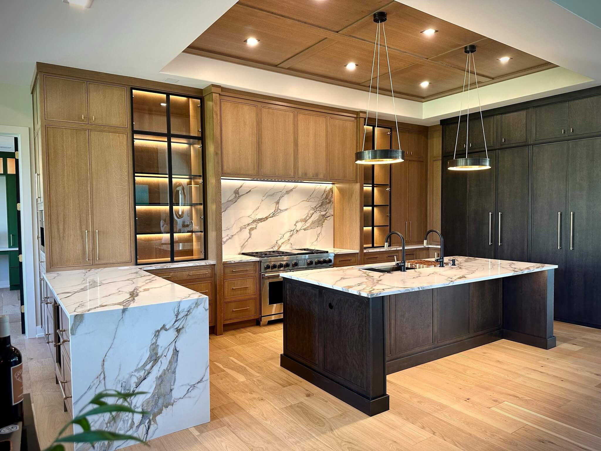 A quarter-sawn white oak kitchen with two-toned stained colors with a grand range alcove space surrounded by black metal framed cabinet doors.