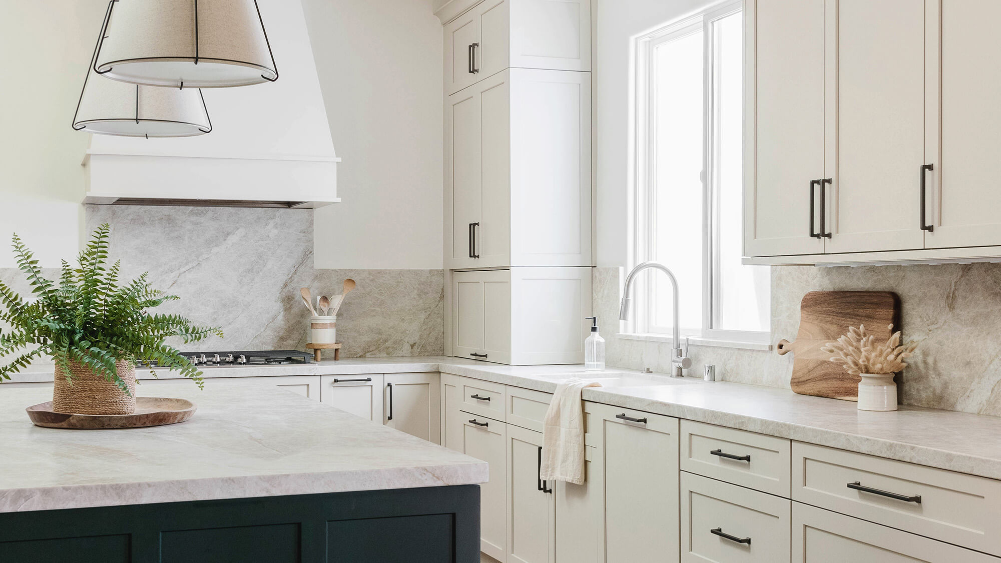 A white kitchen design with a hunter green painted kitchen island and a stunning white painted wood hood.