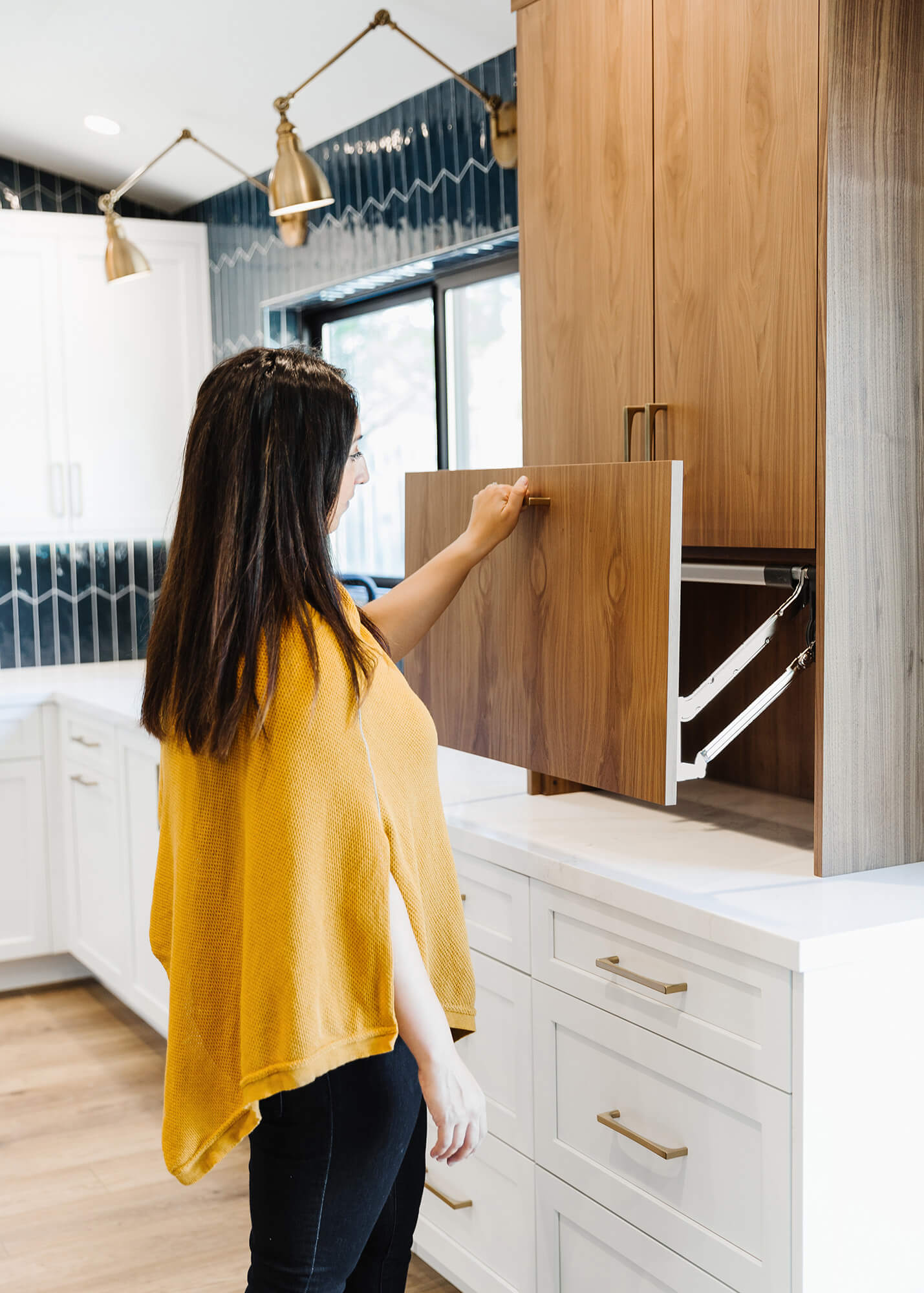 A homeowner opening an appliance cabinet that sits at countertop level with a modern lift-up cabinet door for easy access.