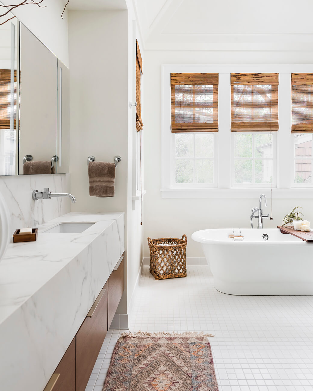 A chic boho styled master bathroom with a spa-like vibe featuring a free standing bath tub and modern floating vanity with a thick countertop.