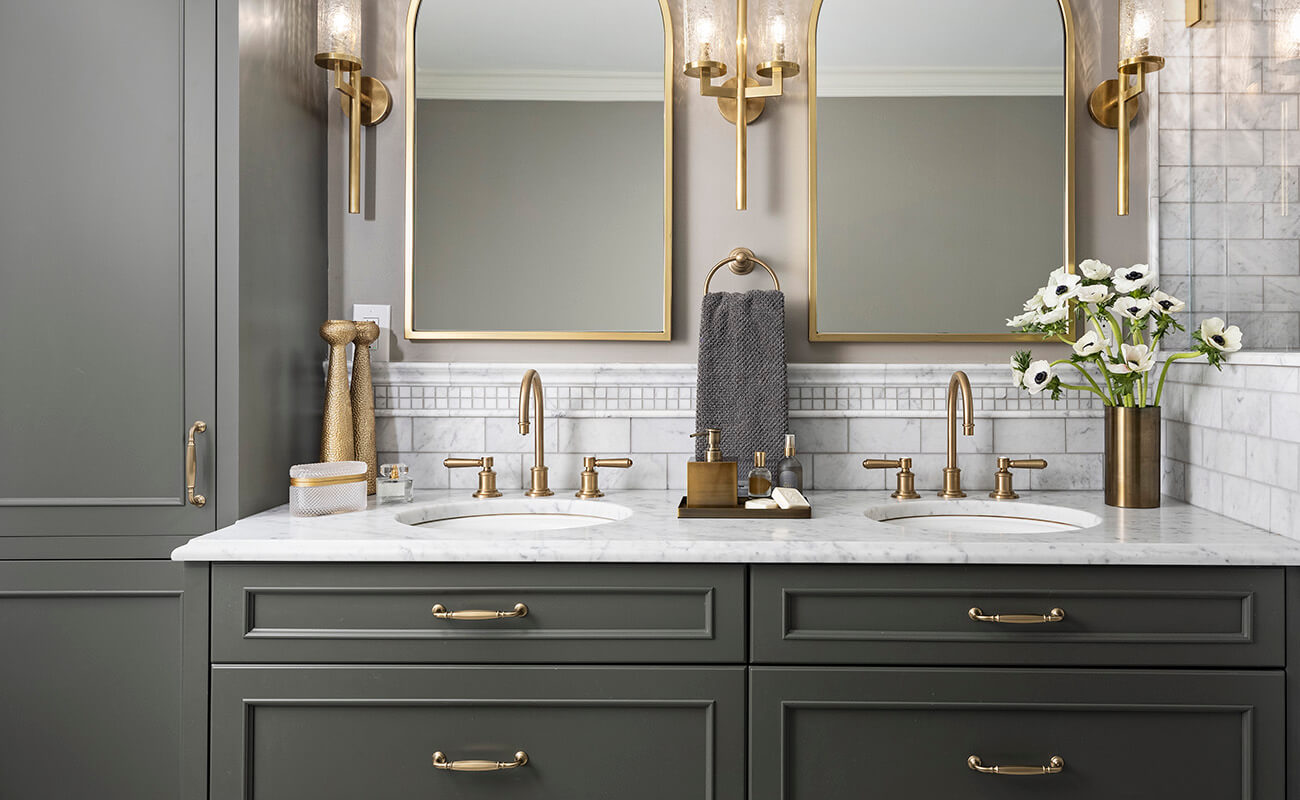 A luxury bathroom design with a traditional styled bathroom vanity with a dark olive green paint color and gold hardware.