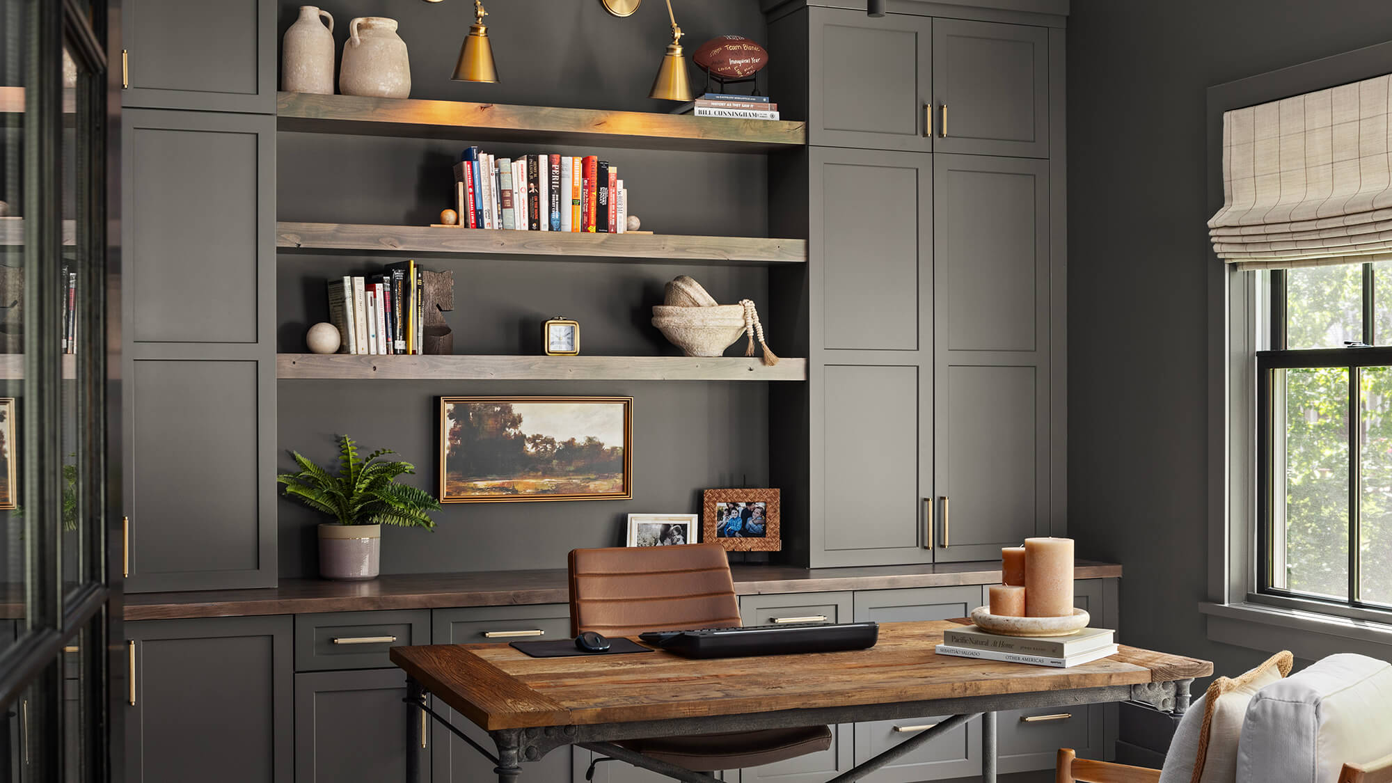 A creative and moody home office design color drenched in a dark green color with accents of gold and dark rustic woos.