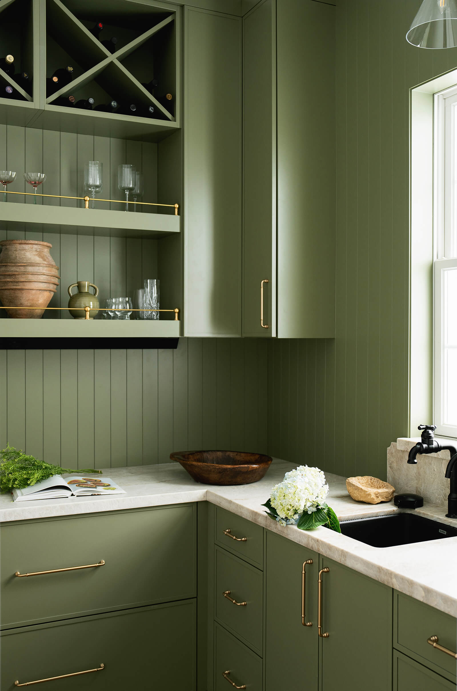 A trending color drenched walk-in pantry featuring an olive green paint color for the cabinets, walls, wood trim, and backsplash.
