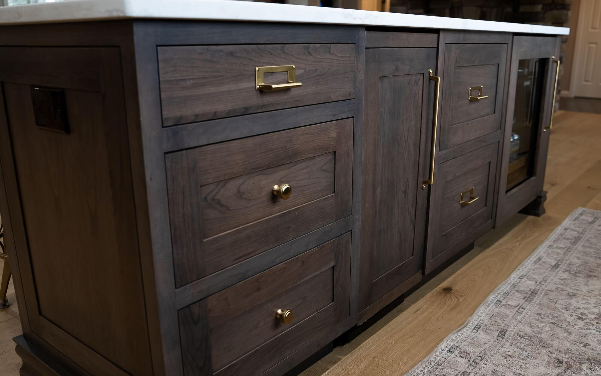 A close up of the dark stained kitchen island that is packed full of storage and function for entertaining guests.