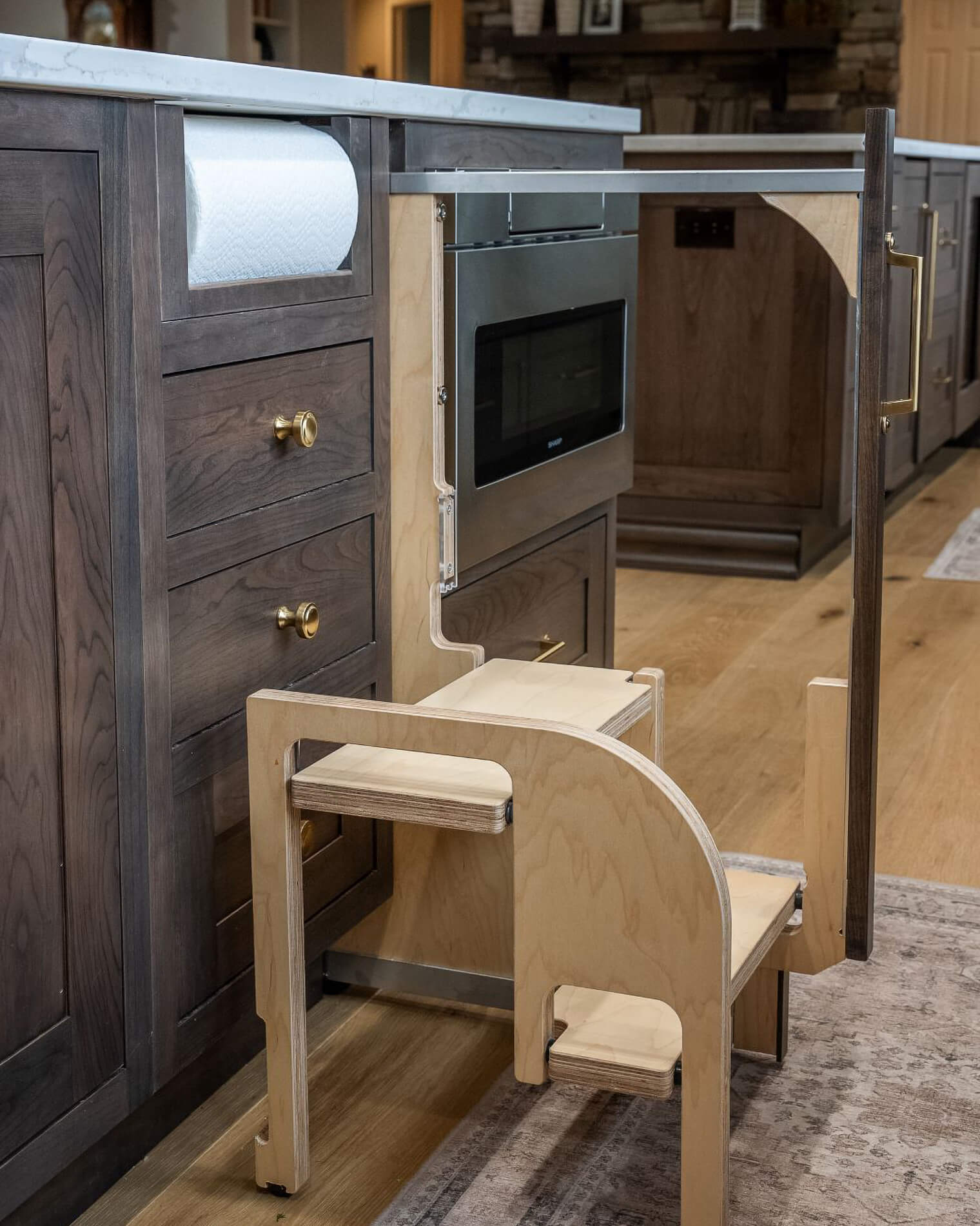 A kitchen island with a pull-out step stool for children to help with food prep and baking tasks.