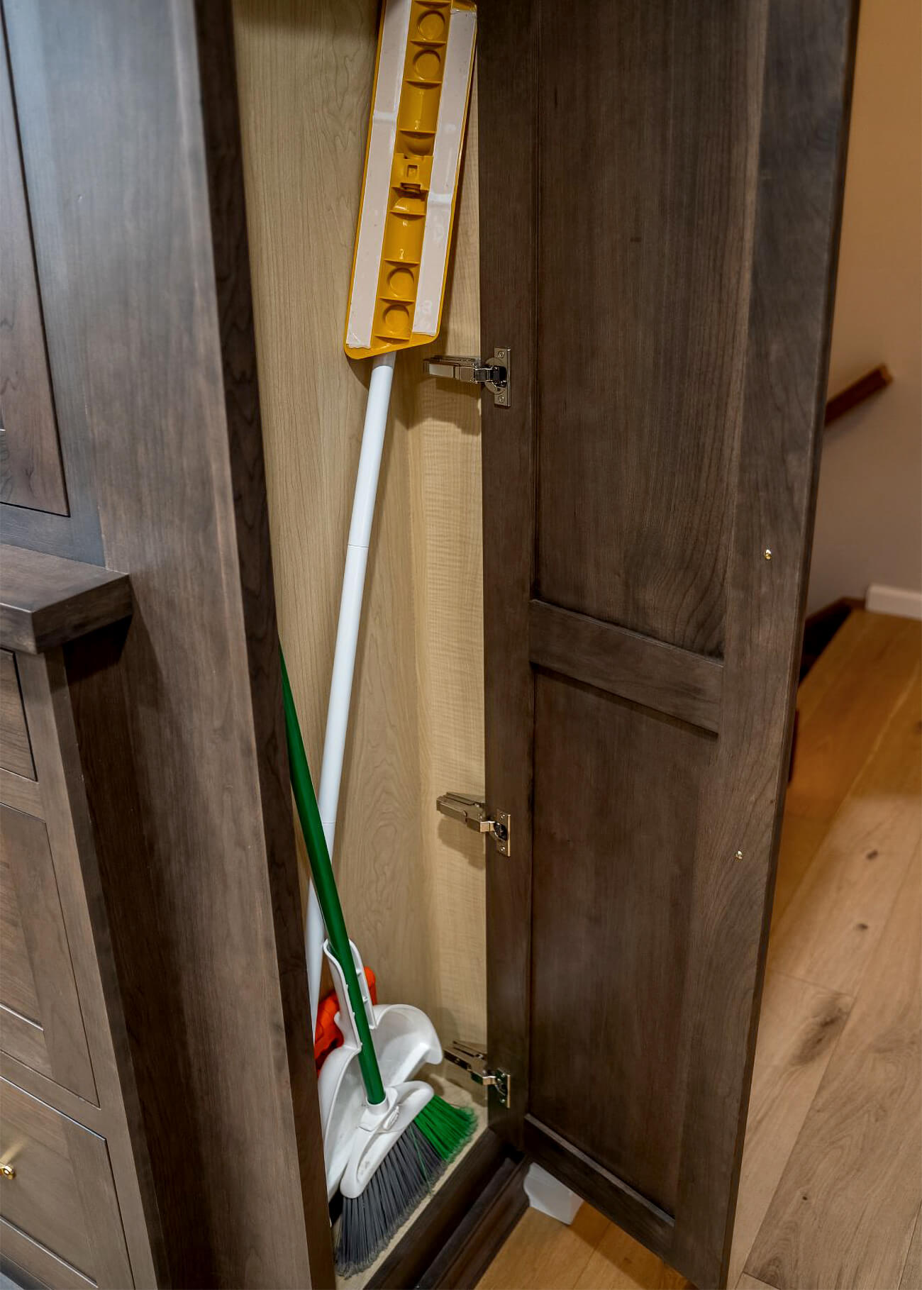 The end of the cabinet opens up to reveal a slim storage space perfect for cleaning supplies like brooms, mops, and more.