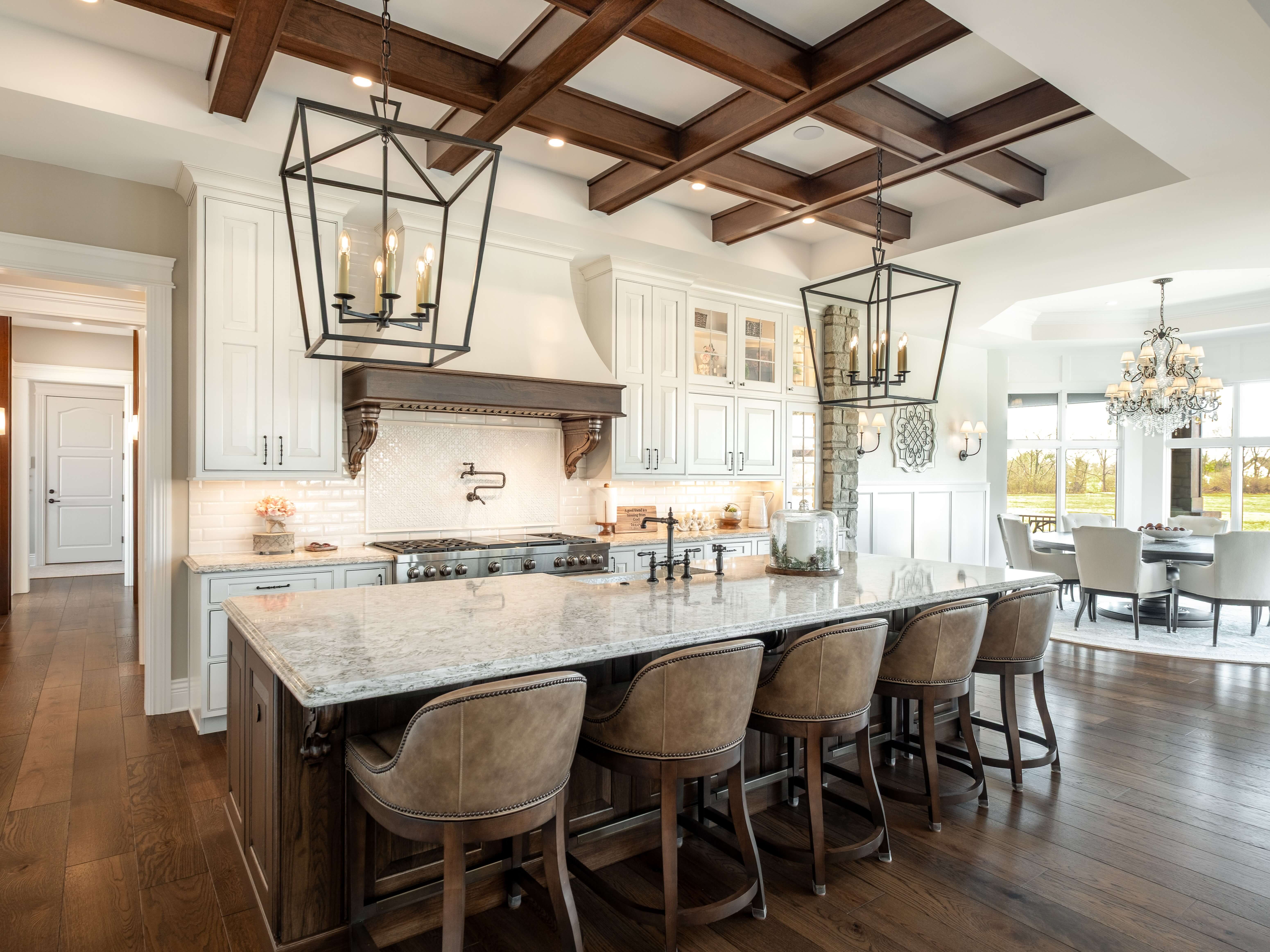 A two-tone traditional styled kitchen design with vaulted ceilings, rustic ceiling beams, a grand wood hood, corbels, turned posts and a large kitchen island. This kitchen has traditional styled inset cabinets.