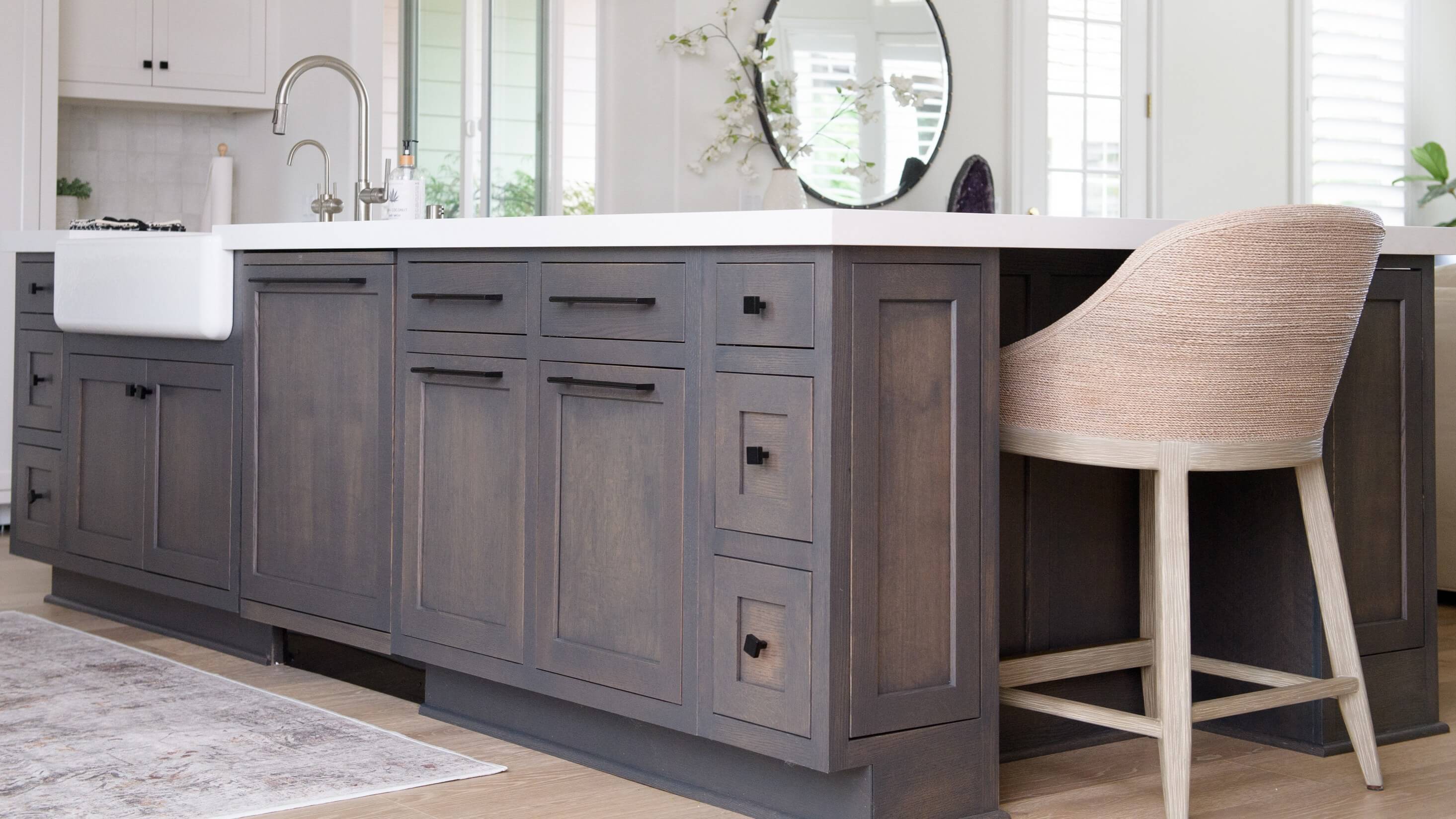 A gray stained kitchen island with inset cabinet doors and a furniture-like construction.