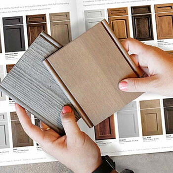 Hands holding finish samples from Dura Supreme Cabinetry.